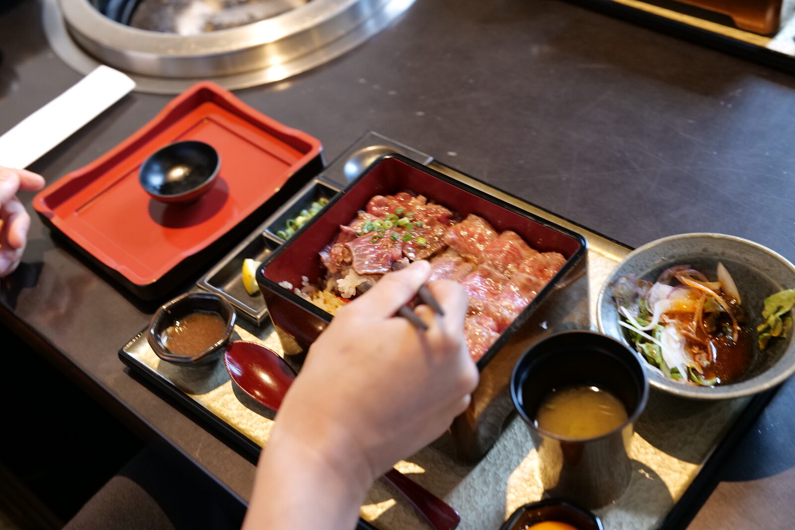 肉重の和牛を持ち上げて卵に絡める様子